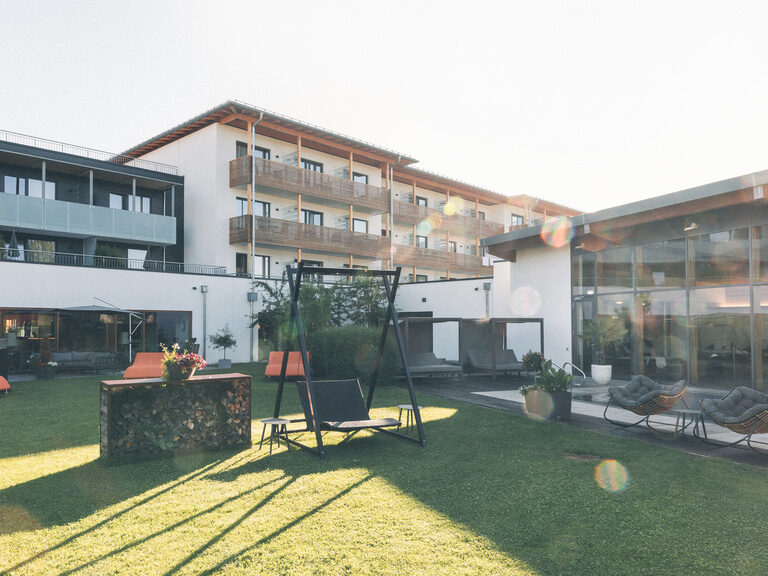 Hotelgarten mit Sonnenliegen und gemütlicher Hollywoodschaukel im Sommer.